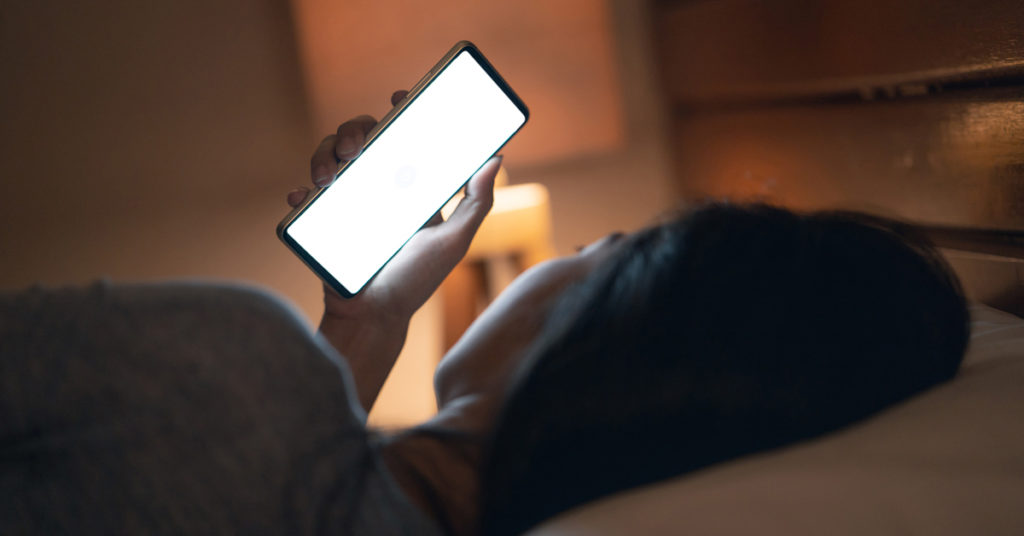 person using a phone late at night in bed